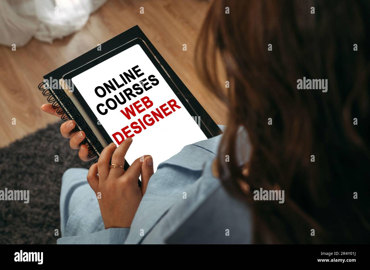 Online learning concept. A woman holds a tablet in her hands on the screen of which it is written - online courses Web designer Stock Photo