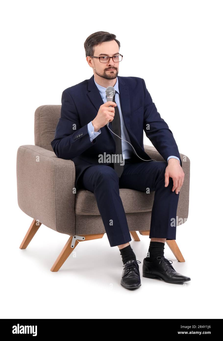 Male journalist with microphone in armchair on white background Stock