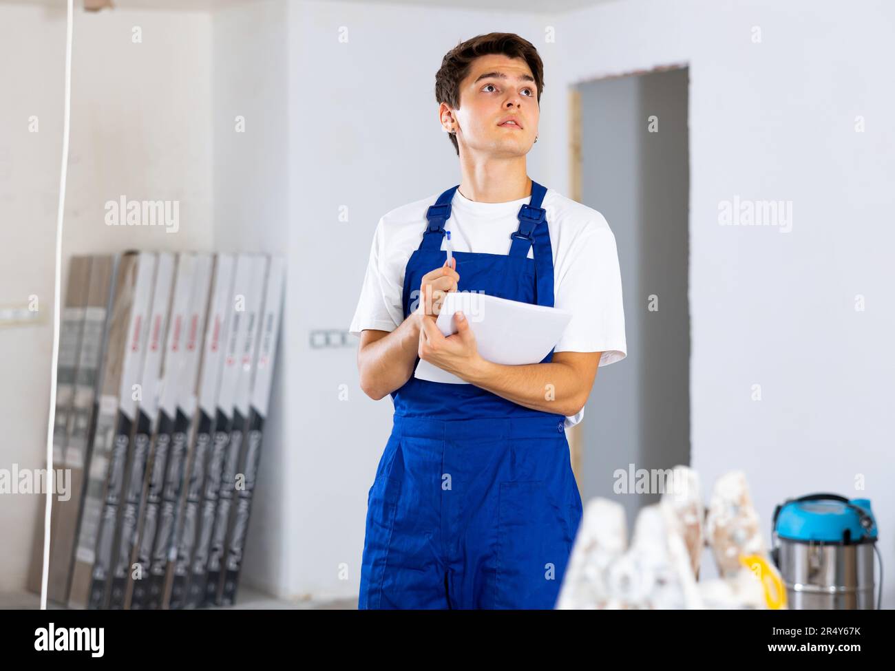 Young builder making checklist while planning indoor building overhaul Stock Photo
