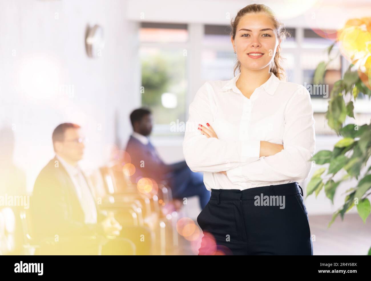 Friendly hostess woman stands at office reception with list of guests and expects invited visitors Stock Photo