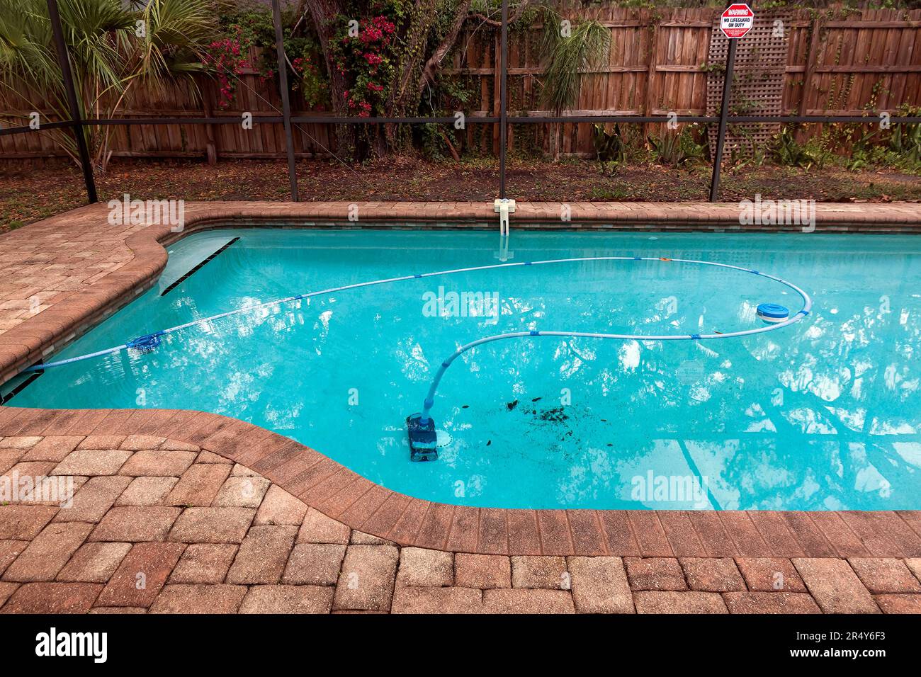 Backyard swimming pool robotic cleaner vacuums the bottom of the pool. Stock Photo