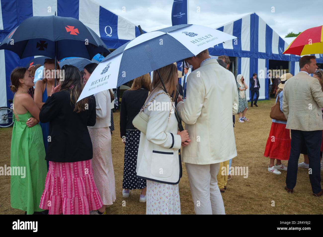 A couple shelter from the rain under an umbrella at Henley Royal Regatta, Henley-on-Thames, 2022 Stock Photo