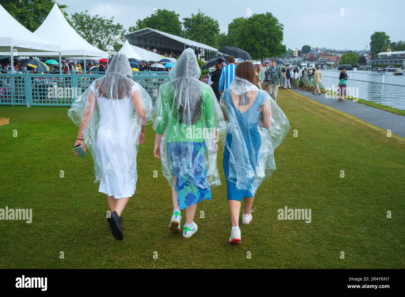 Three young women keep the rain off with transparent plastic parkas in the Regatta enclosure  at Henley Royal Regatta, Henley-on-Thames, 2022 Stock Photo