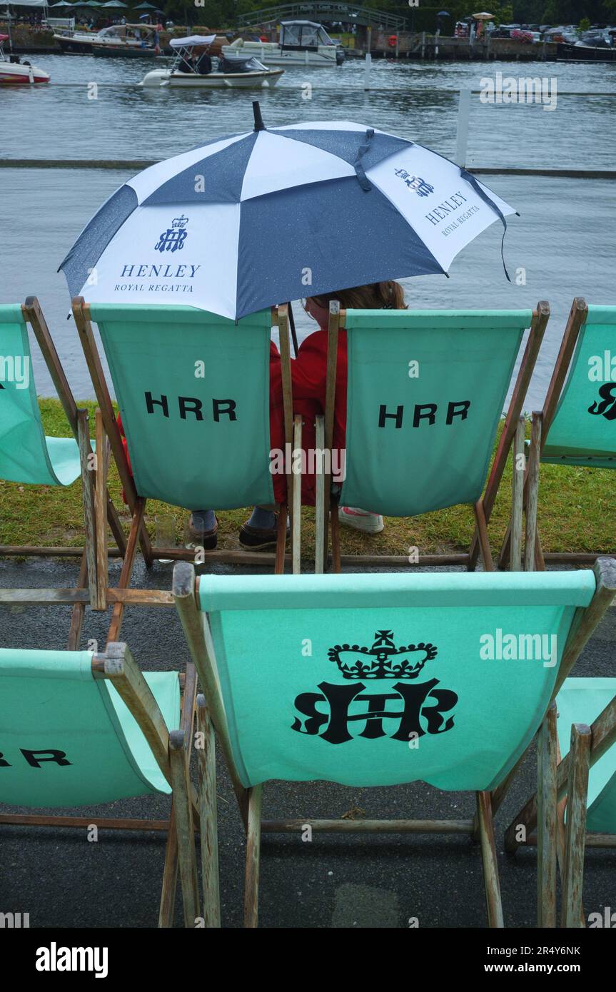 A couple shelter from the rain under a colourful blue and white umbrella  at Henley Royal Regatta, Henley-on-Thames, 2022 Stock Photo