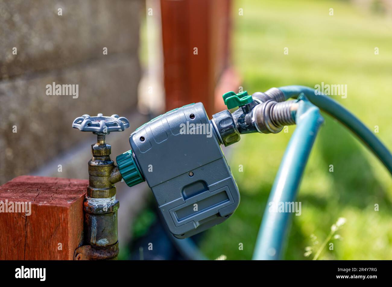 Garden water timer on a spigot with a splitter and hoses Stock Photo