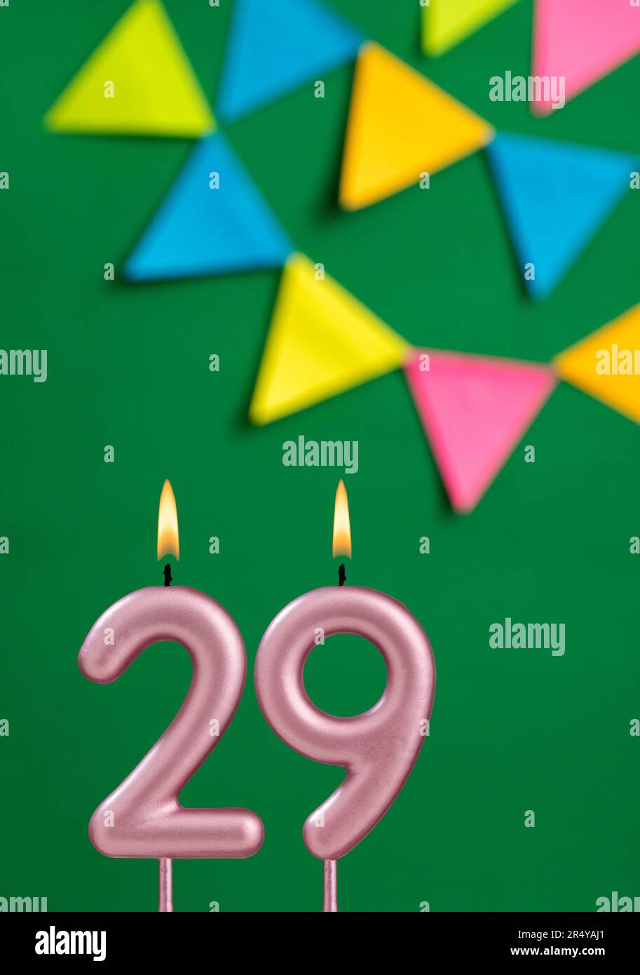 Number 29 candle - Birthday celebration on green background Stock Photo