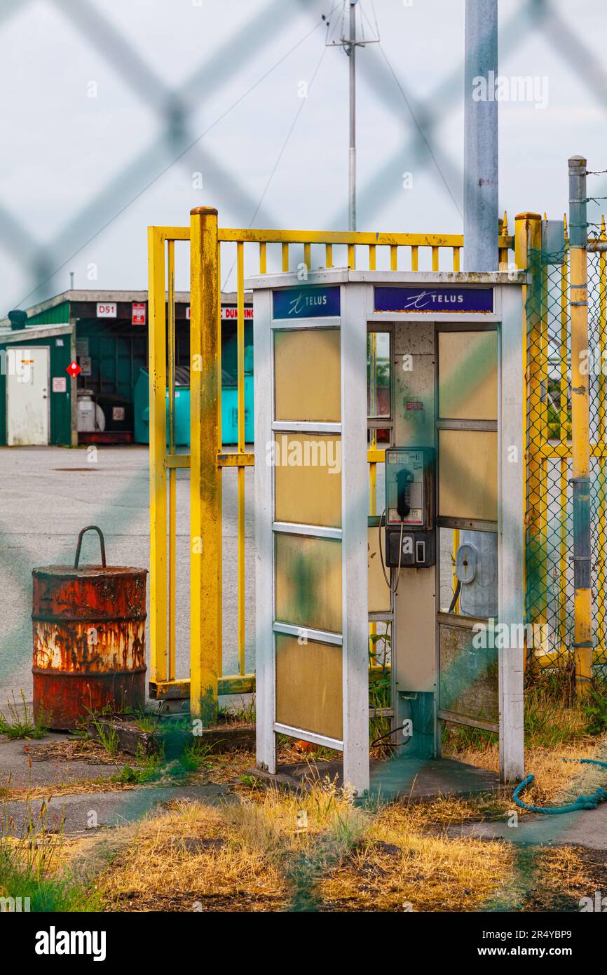 Old style telephone booth behind a chainlink fence in Steveston British Columbia Canada Stock Photo