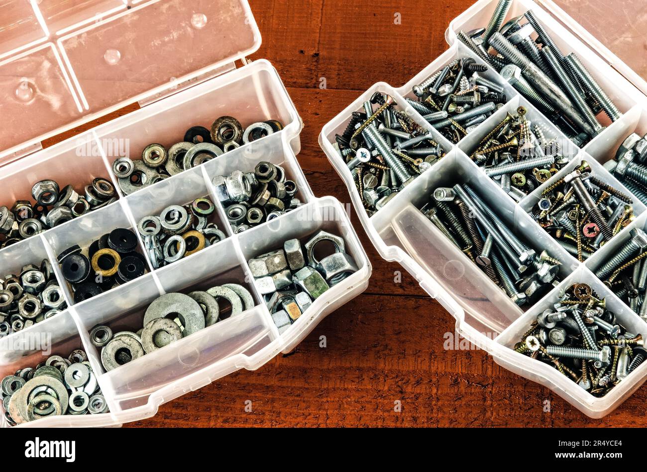 Silver and gold metal screws. Bolts and screws in plastic container