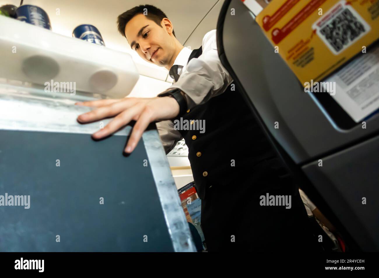 Flight attendant serving meal and drinks to passengers sitting in a