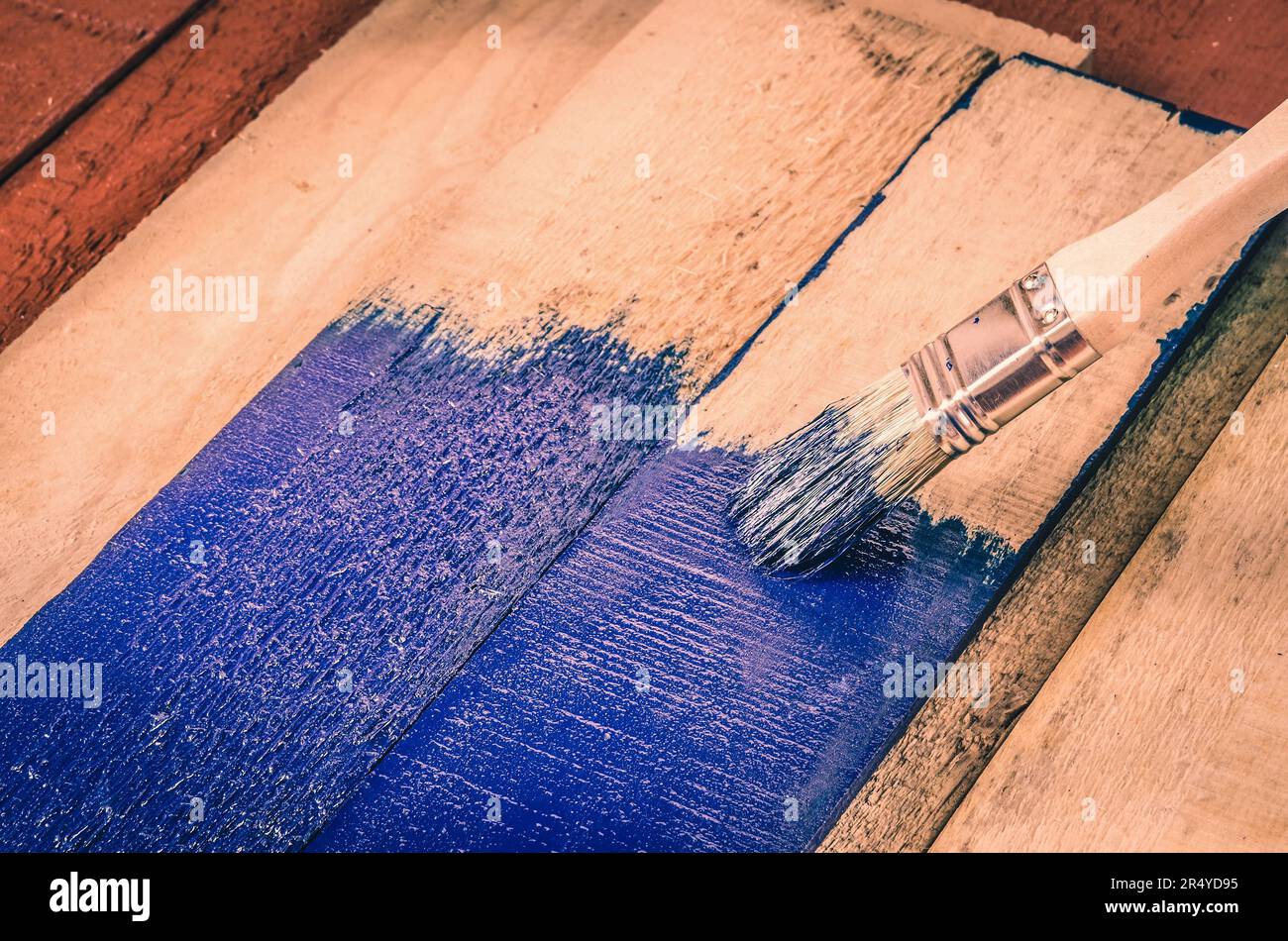 Brush, paint and wooden boards. Painting the boards with blue paint