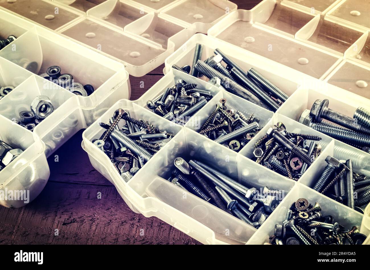 Silver and gold metal screws. Bolts and screws in plastic container