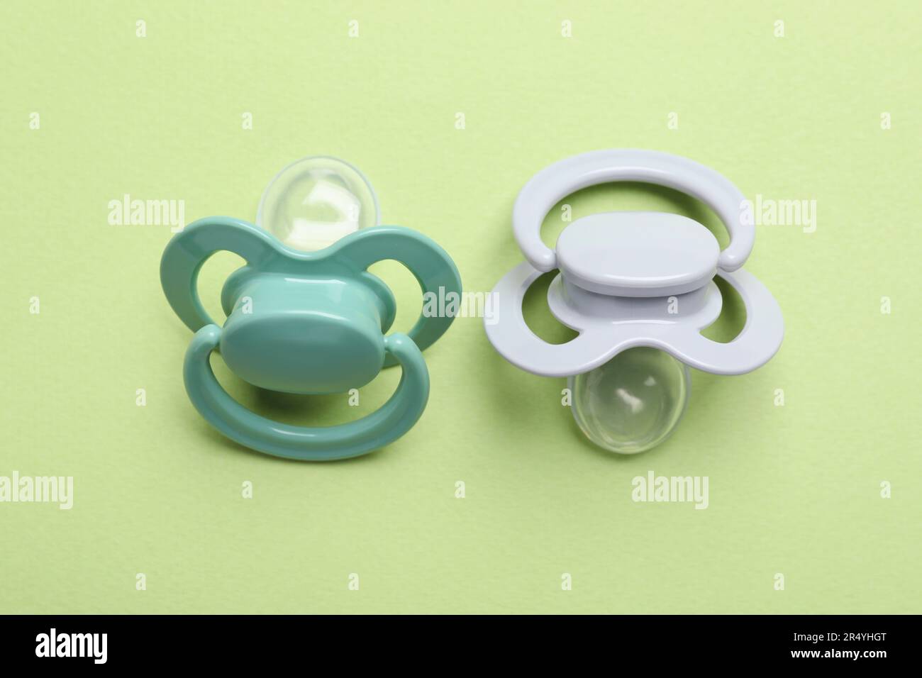 Two baby pacifiers on pale green background Stock Photo