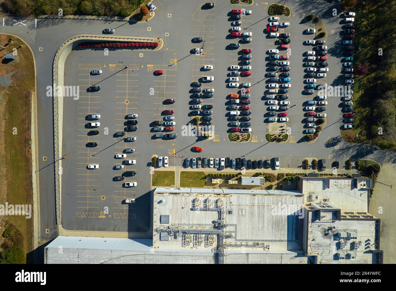 Many associate cars parked on big parking lot in front of industrial