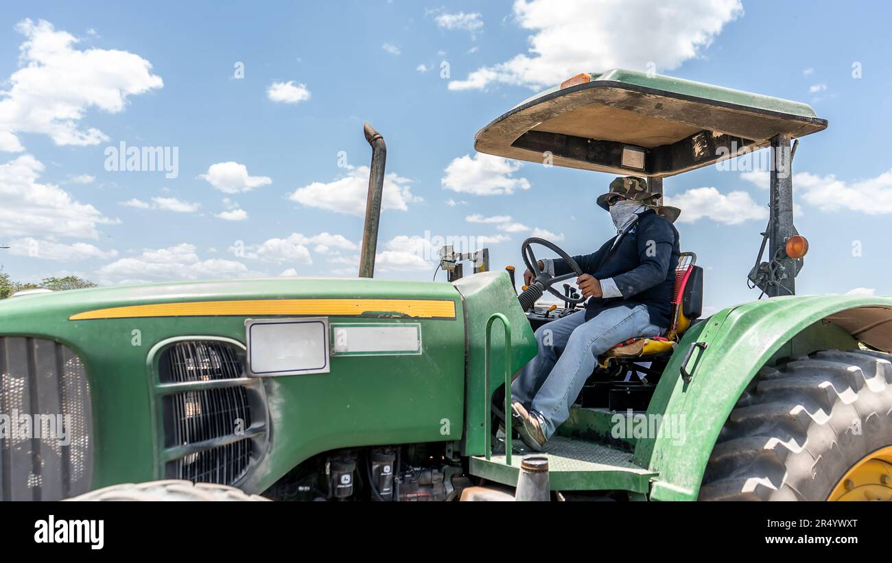 Farmer driving a green tractor under the blue sky Stock Photo - Alamy