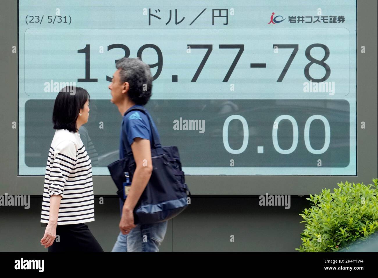 People walk past at an electronic board showing the U.S. dollar and