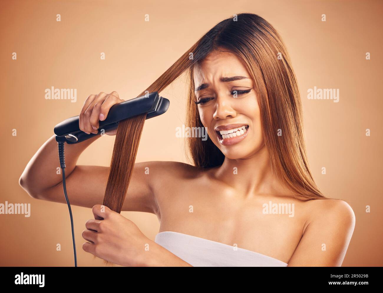 Woman with flat iron, haircare and heat damage, mistake and worried about hair loss on studio background. Electric straightener, female model with Stock Photo