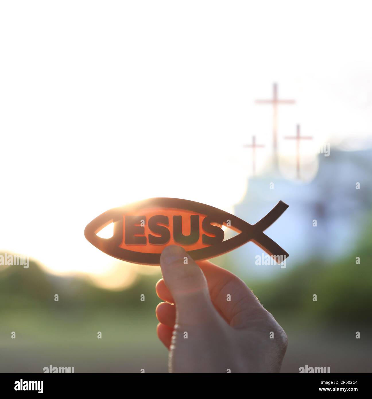 The brightly rising sunrise and the Christian symbols fish figures Ichthys and Jesus and the church cross Stock Photo