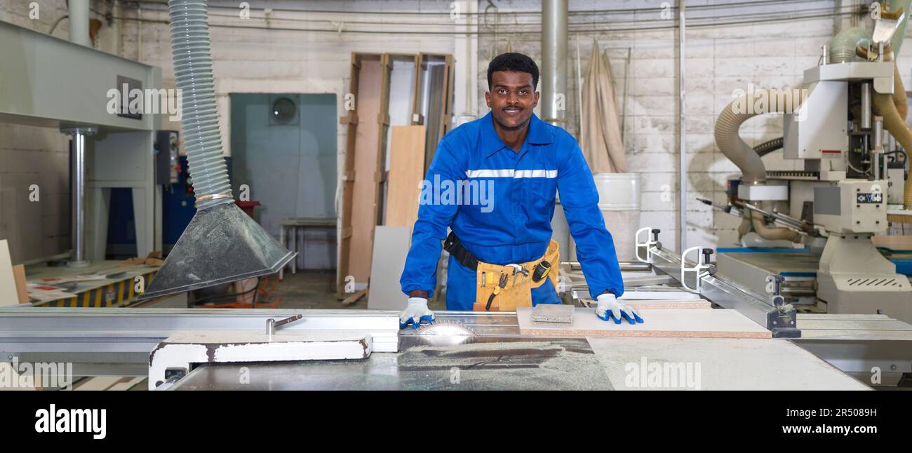Young technician in blue mechanic jumpsuit, protective glove and yellow ...