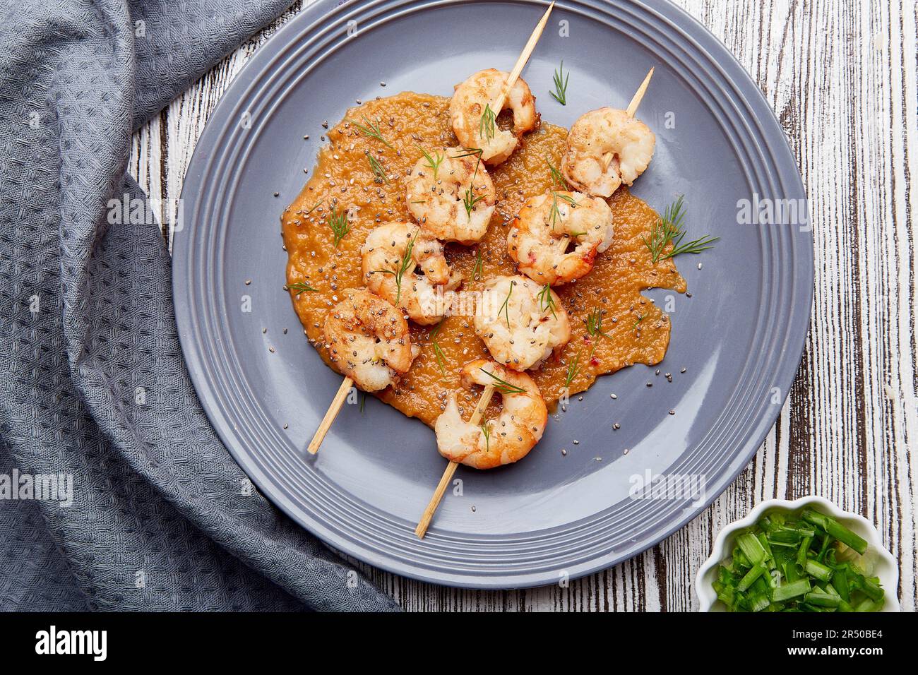 Party seafood snacks. Grilled prawns on skewers on the plate. Seafood barbecue, roast shrimps top view. Stock Photo
