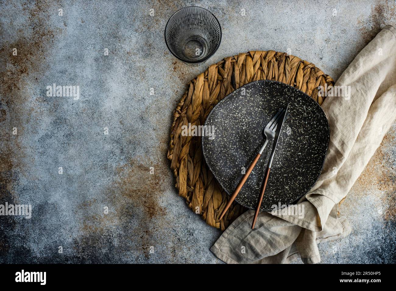 Minimalistic table setting with rustic napkin and stoneware on concrete table Stock Photo