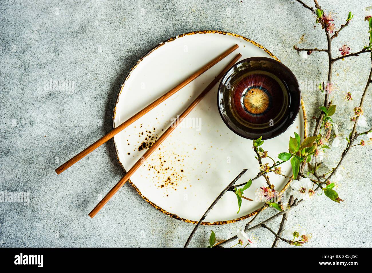 Spring table setting with chopsticks decorated with blooming cherry tree branches Stock Photo