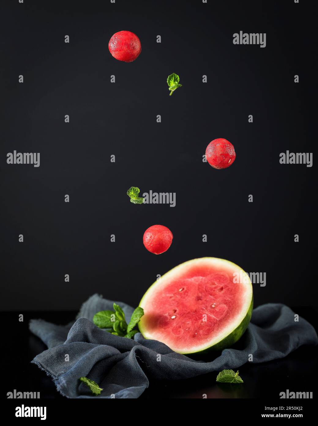 Half a watermelon and flying melon balls Stock Photo