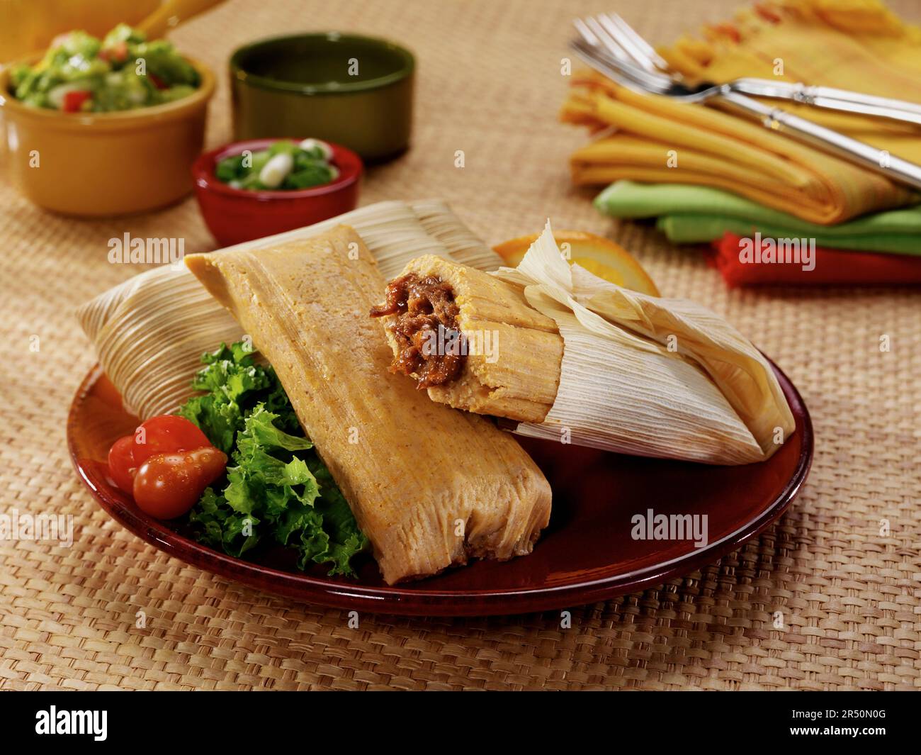 Mexican Pork Tamales Steamed In Corn Husks With Lettuce And Tomato In A mexican-pork-tamales-steamed-in-corn-husks-with-lettuce-and-tomato-in-a