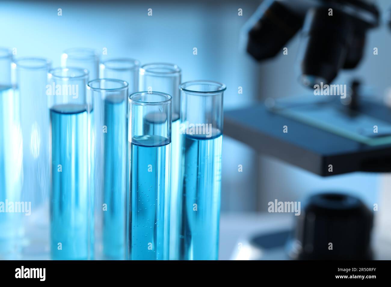 Test tubes with light blue liquid near microscope in laboratory ...