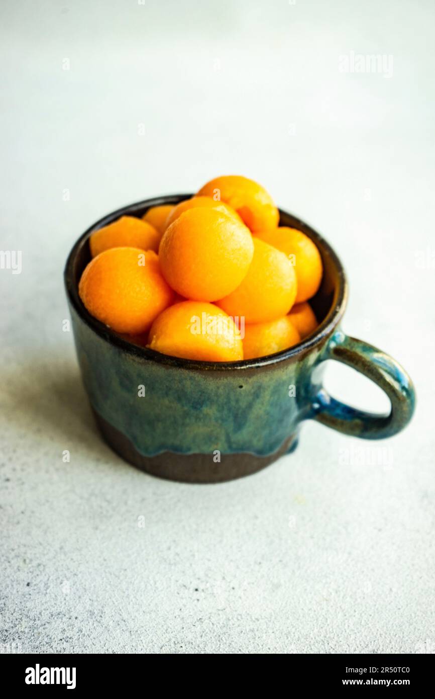 Balls of ripe cantaloupe melon in the ceramic cup on concrete table for dessert meal Stock Photo