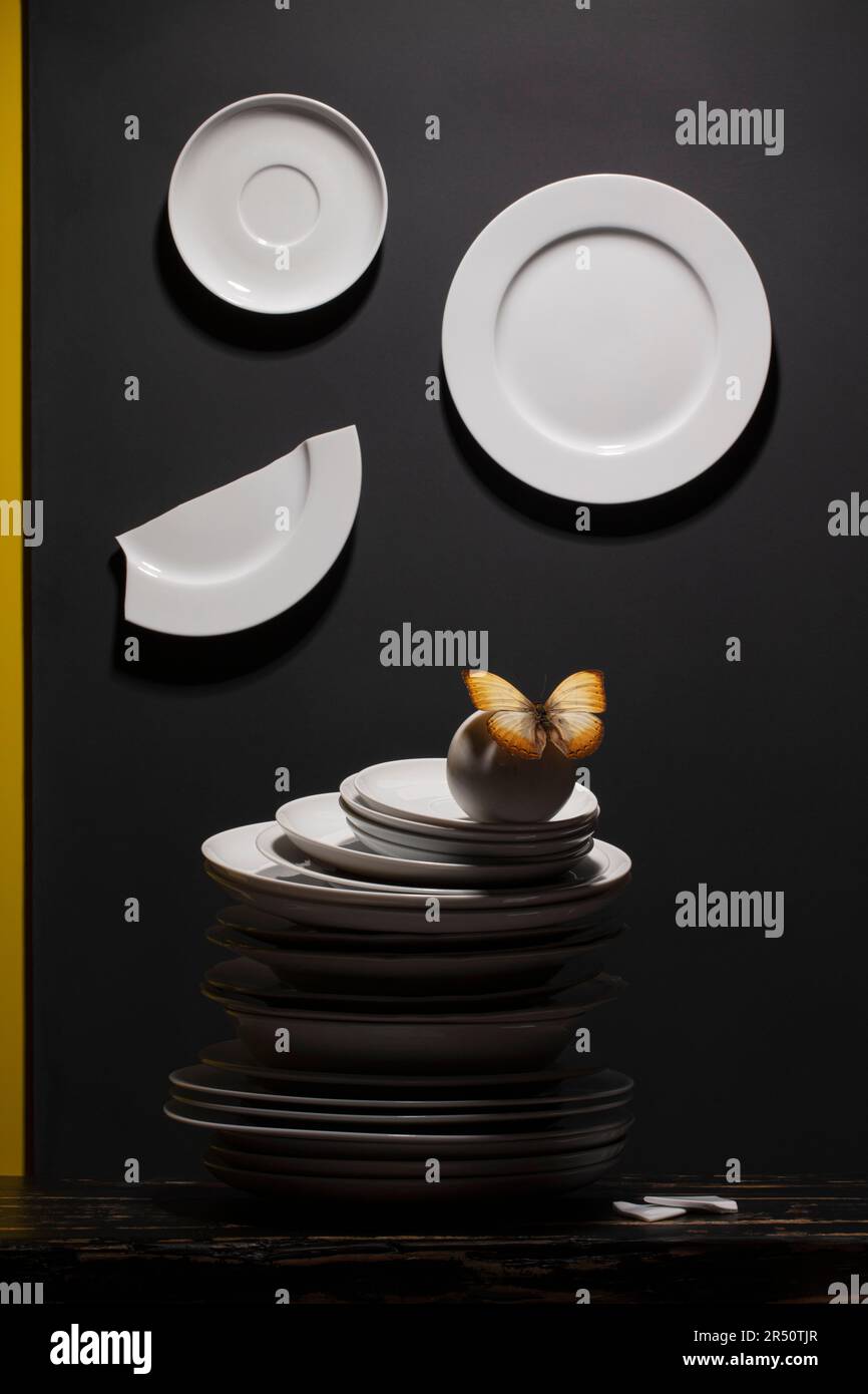 White plates and pile of plates with a butterfly on black background Stock Photo