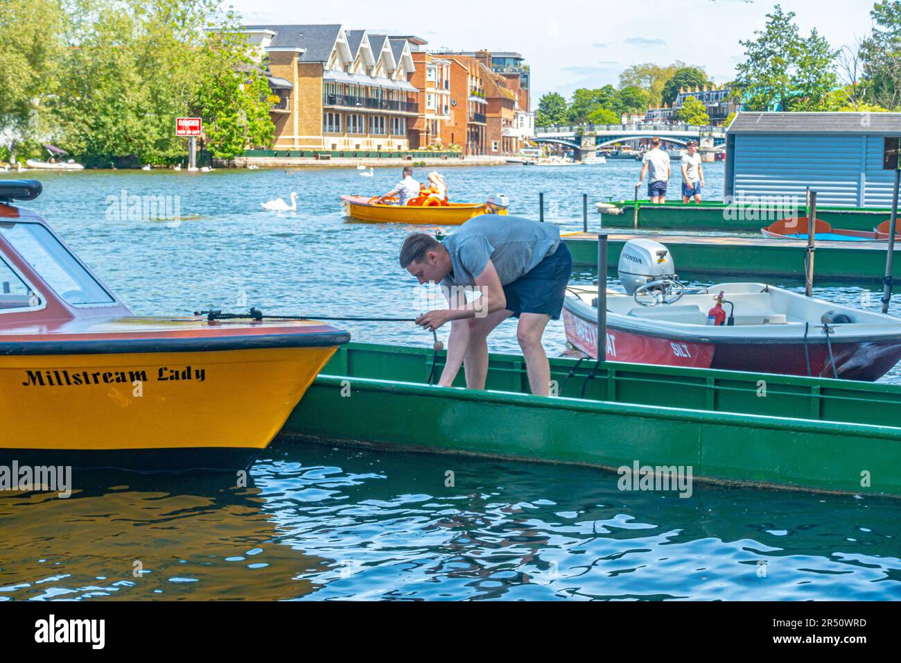 A man ties up a hire boat in The River Thames at Windsor in Berkshire, UK Stock Photo