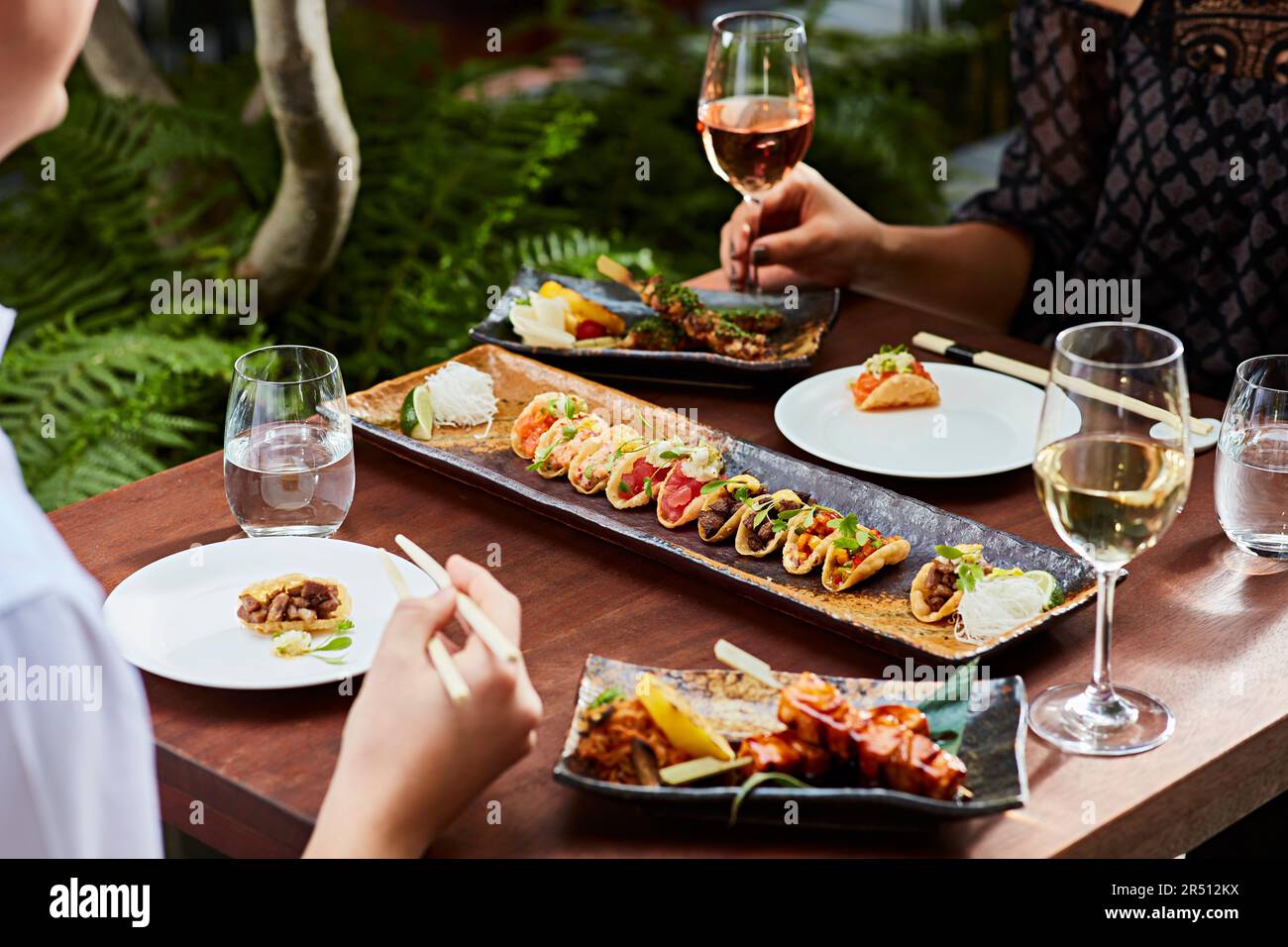 Two people eating mini tacos and drinking wine Stock Photo