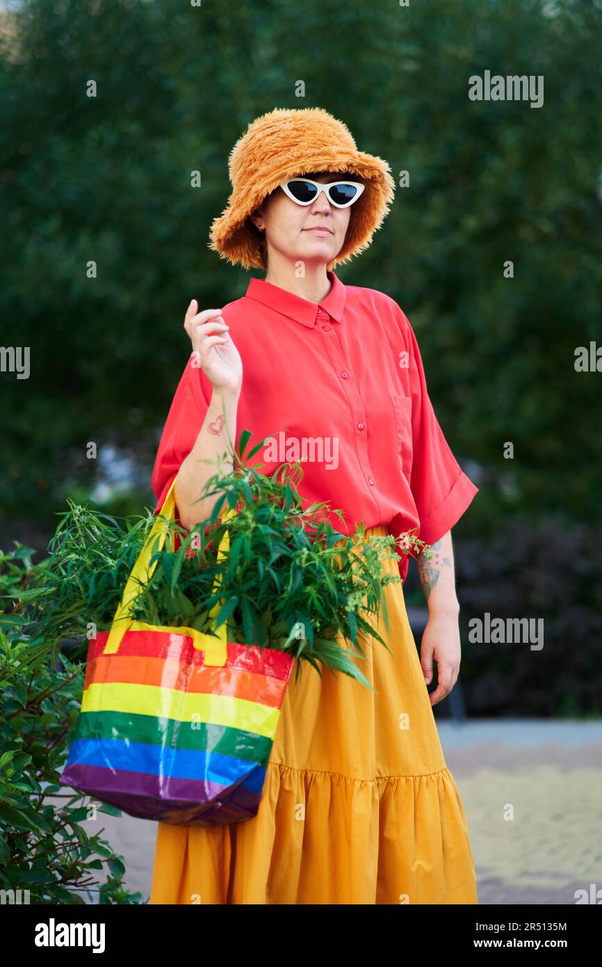 Bright looking female in red t-shirt and yellow skirt with LGBT colors bag full of canabis . High quality photo Stock Photo