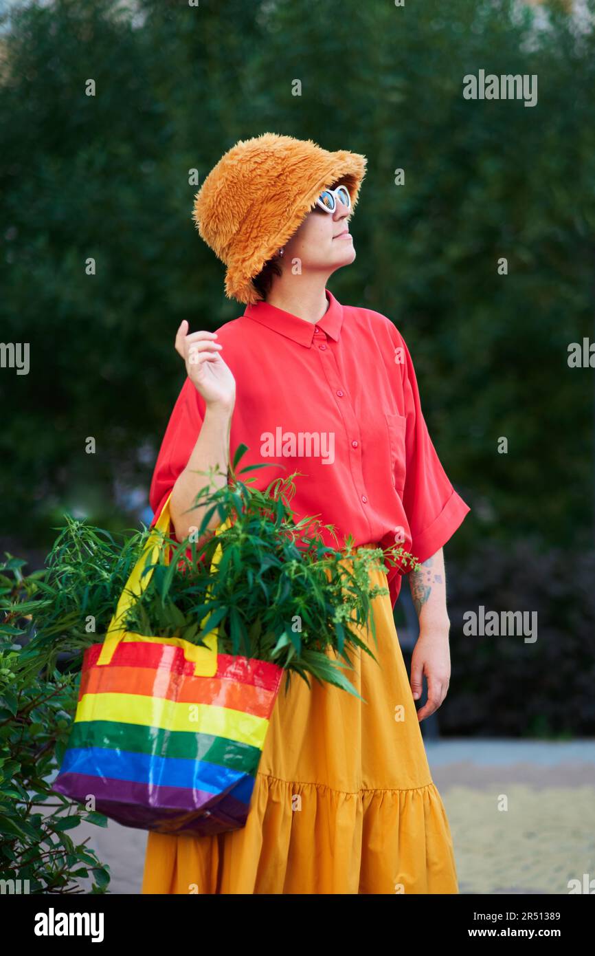 Bright looking female in red t-shirt and yellow skirt with LGBT colors bag full of canabis . High quality photo Stock Photo