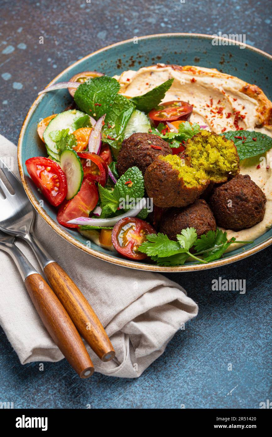 Arab meal with fried falafel, hummus, vegetables salad with fresh green cilantro and mint leaves (Middle Eastern) Stock Photo