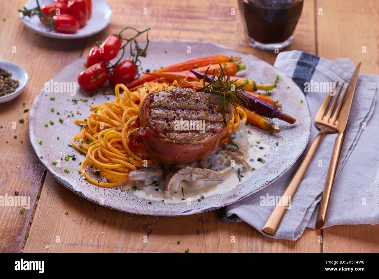 Fillet of beef wrapped in ham with noodles and vegetables Stock Photo