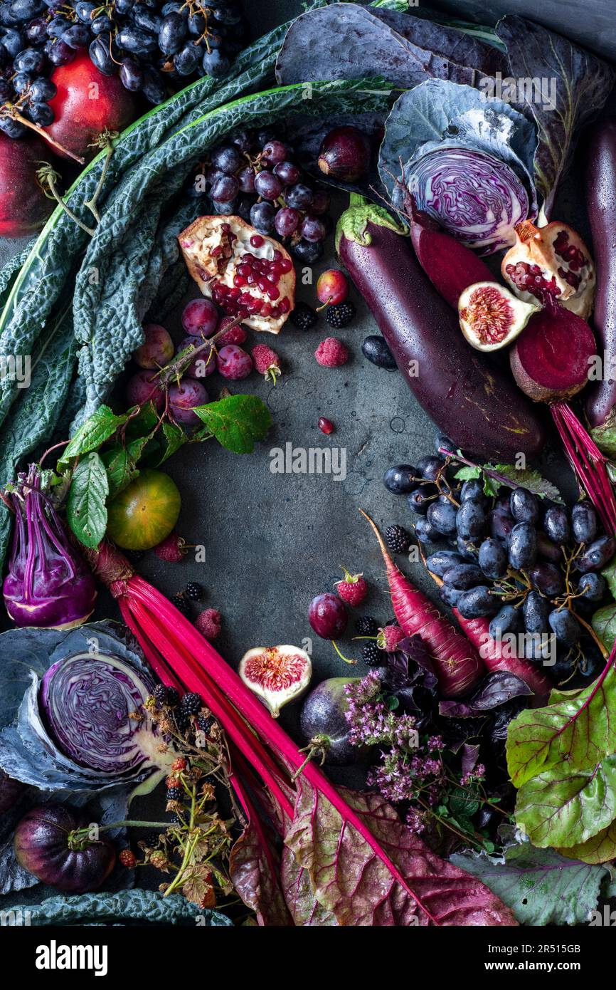 Autumn still life with vegetables and fruit in purple, arranged around ...