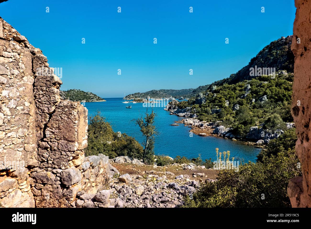 Yachts seen through castle ruins on the Lycian Way, Üçağız, Turkey Stock Photo