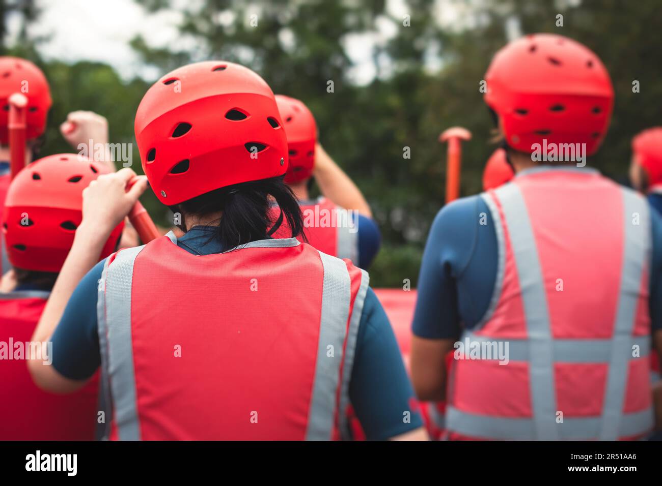 Group of sportsmen in wetsuits with paddles in helmets and life jackets