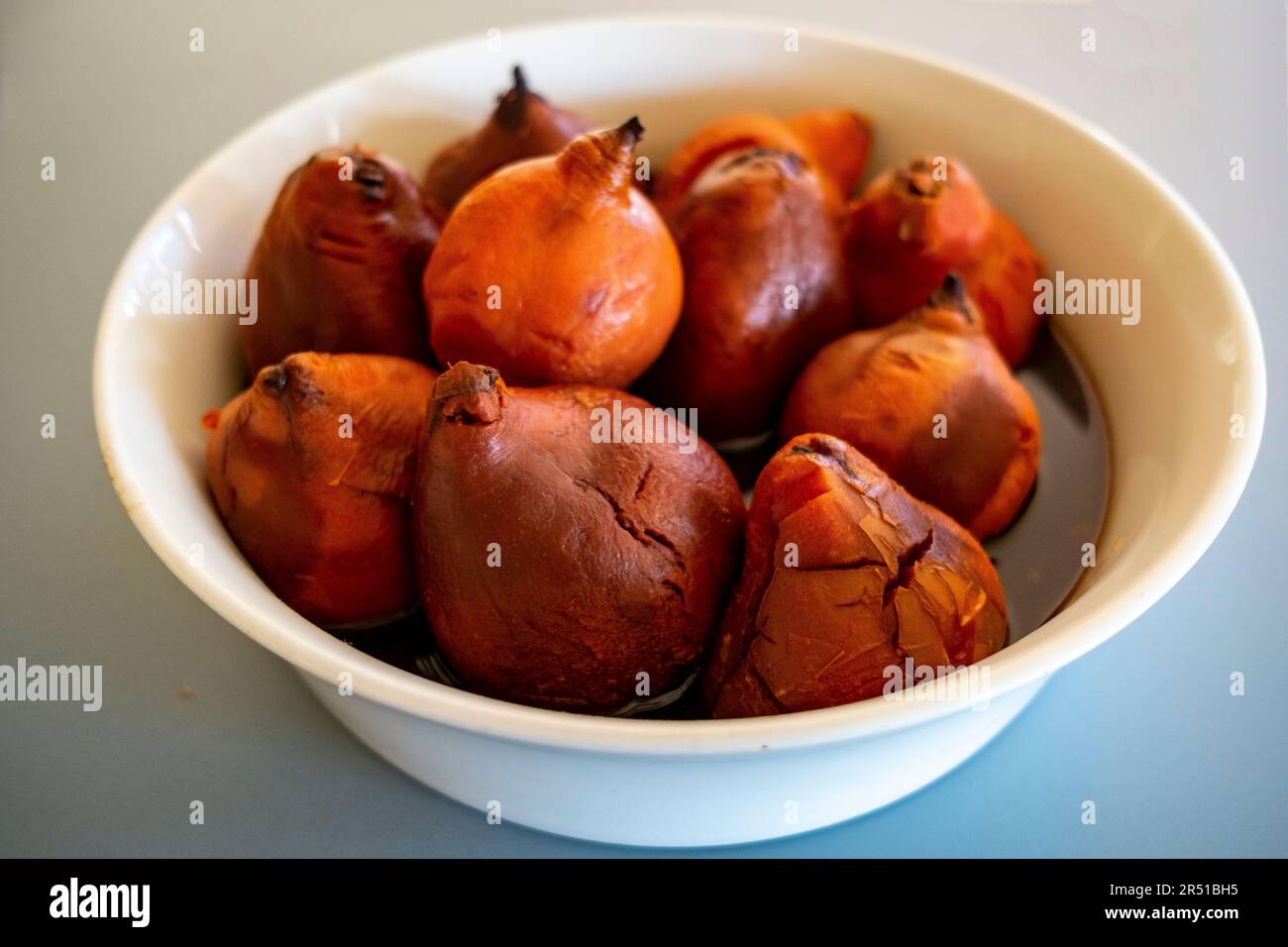 Oven roasted quinces in cinnamon spiced red wine syrup to a recipe by Maggie Beer Stock Photo