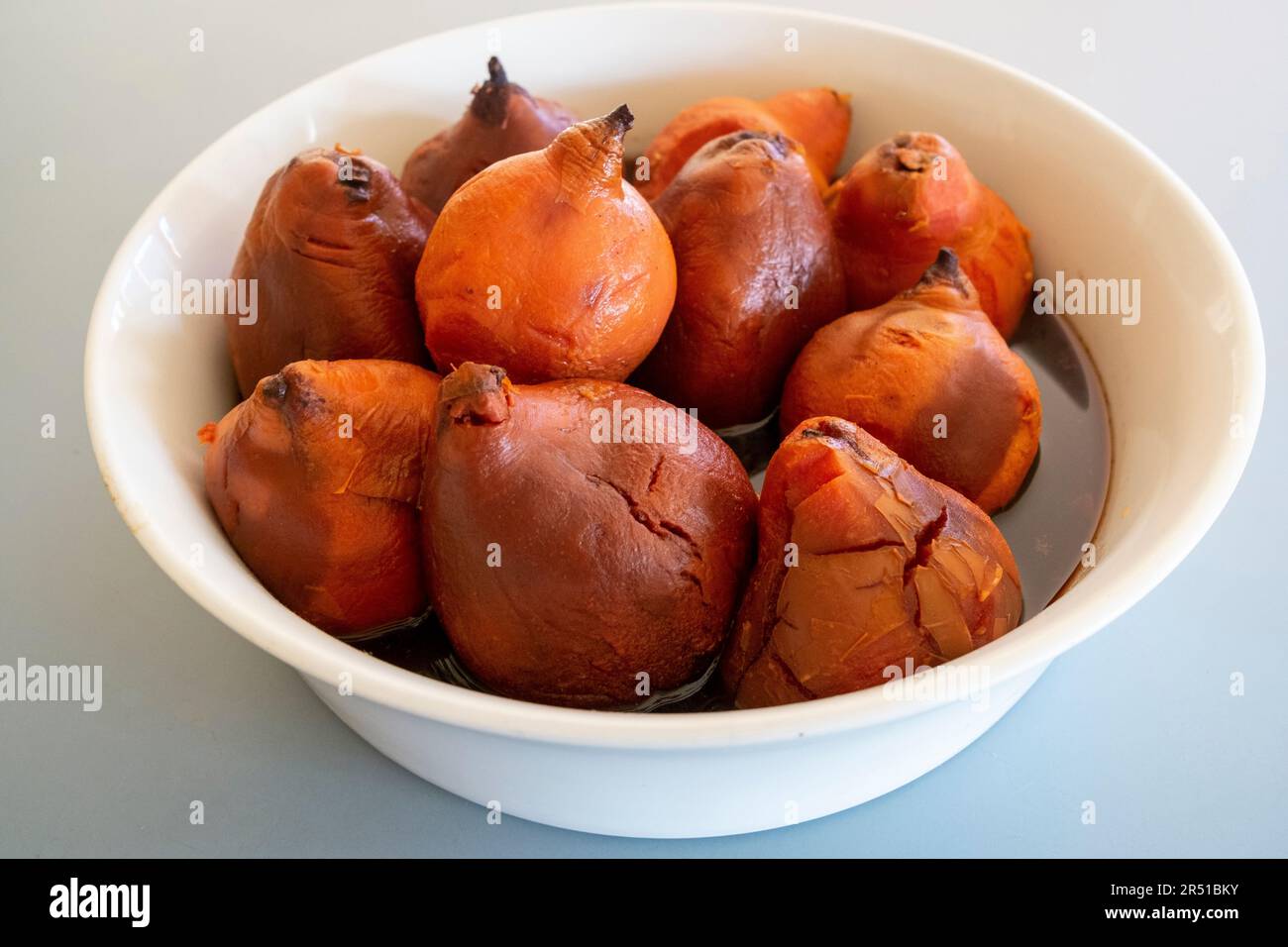 Oven roasted quinces in cinnamon spiced red wine syrup to a recipe by Maggie Beer Stock Photo