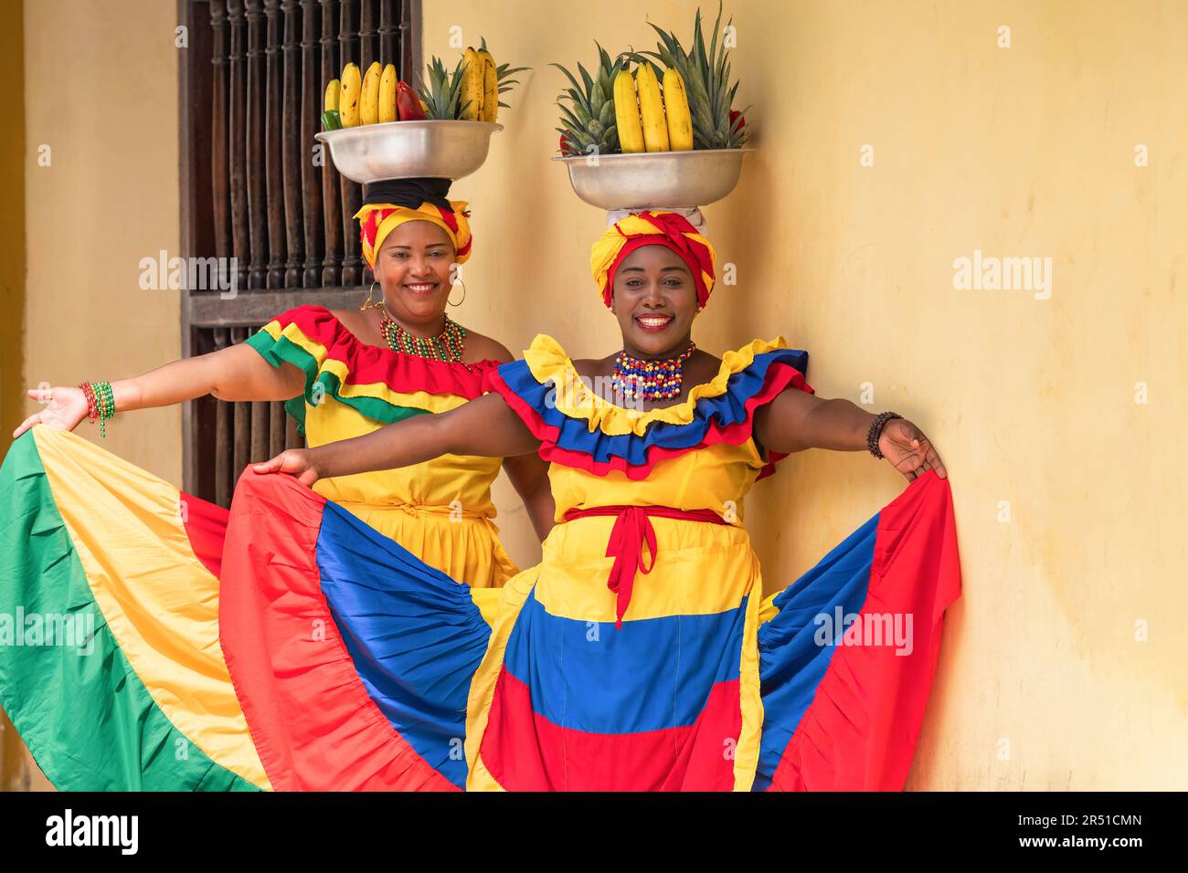 Happy, smiling Palenquera fresh fruit street vendors in the Old Town of Cartagena, Colombia. Cheerful Afro-Colombian women in traditional clothing. Stock Photo
