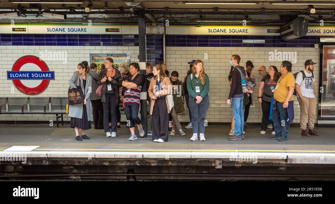 A group of people wait for for an underground train on the platform at Sloane Square tube station in London. Stock Photo