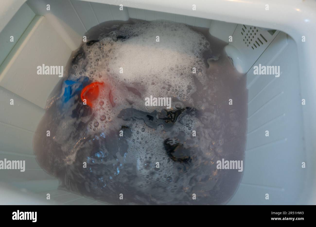 Dirty clothes in top loading washing machine. Clothes with bubble of laundry detergent in