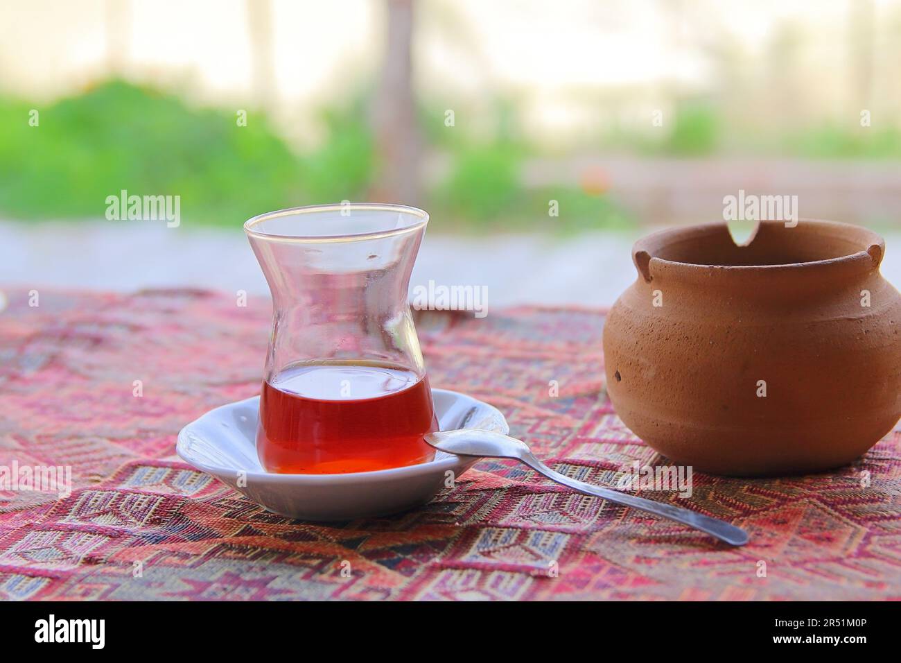 Photo taken in Turkey. The picture shows a small glass of strong tea called - armouts on a traditional Turkish rug spread out on the table. Near a pot Stock Photo