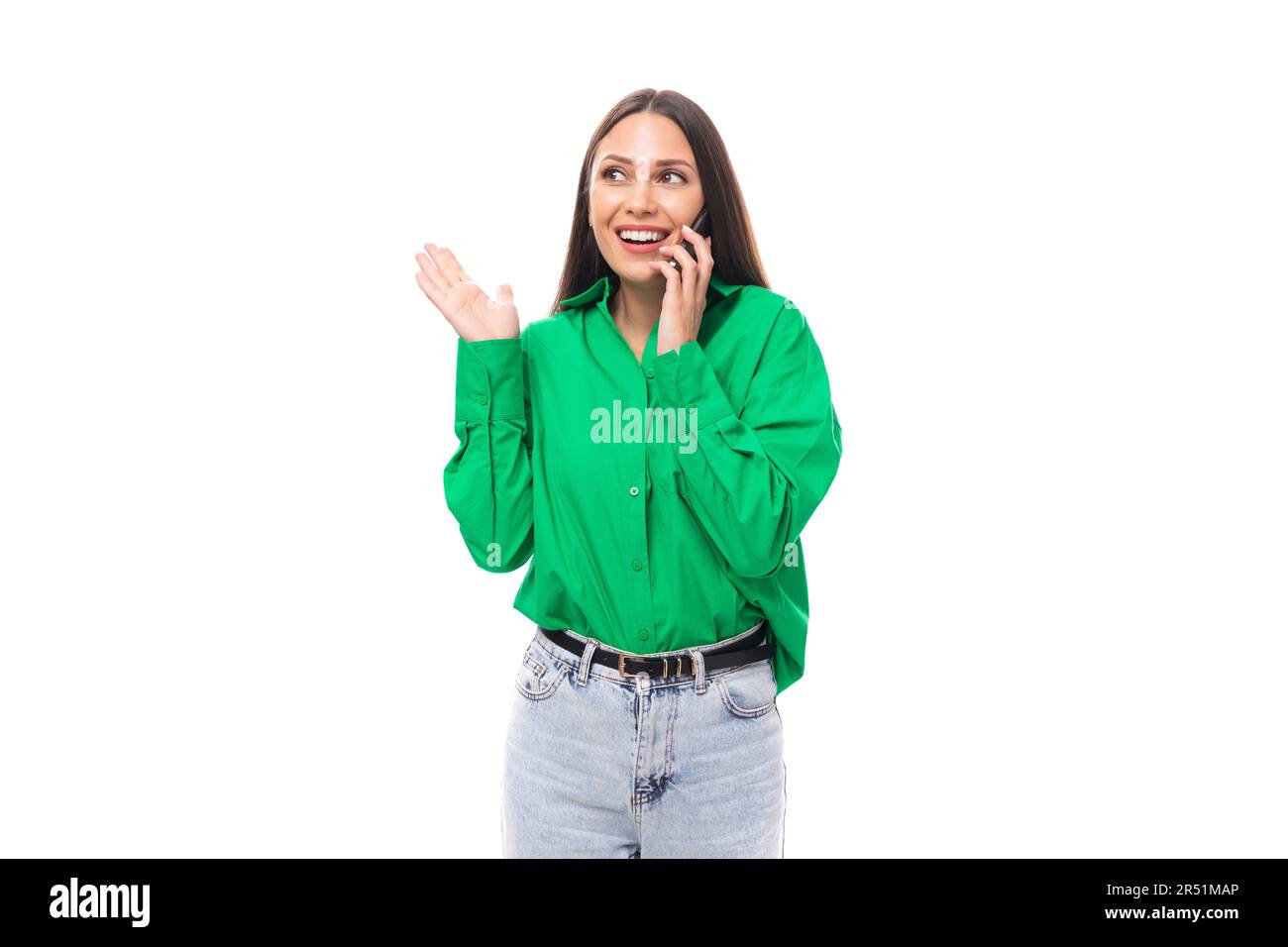 portrait of a smart pensive slim cute brown-eyed brunette woman dressed in a green shirt chatting on the phone on a white background with copy space Stock Photo