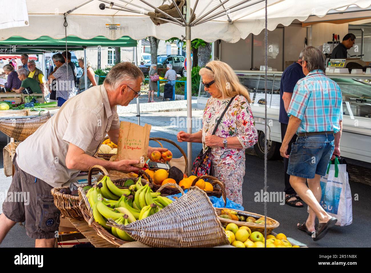Market trader selling fruit and vegetables to customer on market day - La Roche Posay, Vienne (86), France. Stock Photo