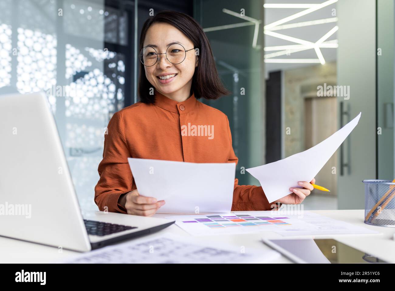 Manager Asian Report Young successful asian financier behind paper work inside office ...