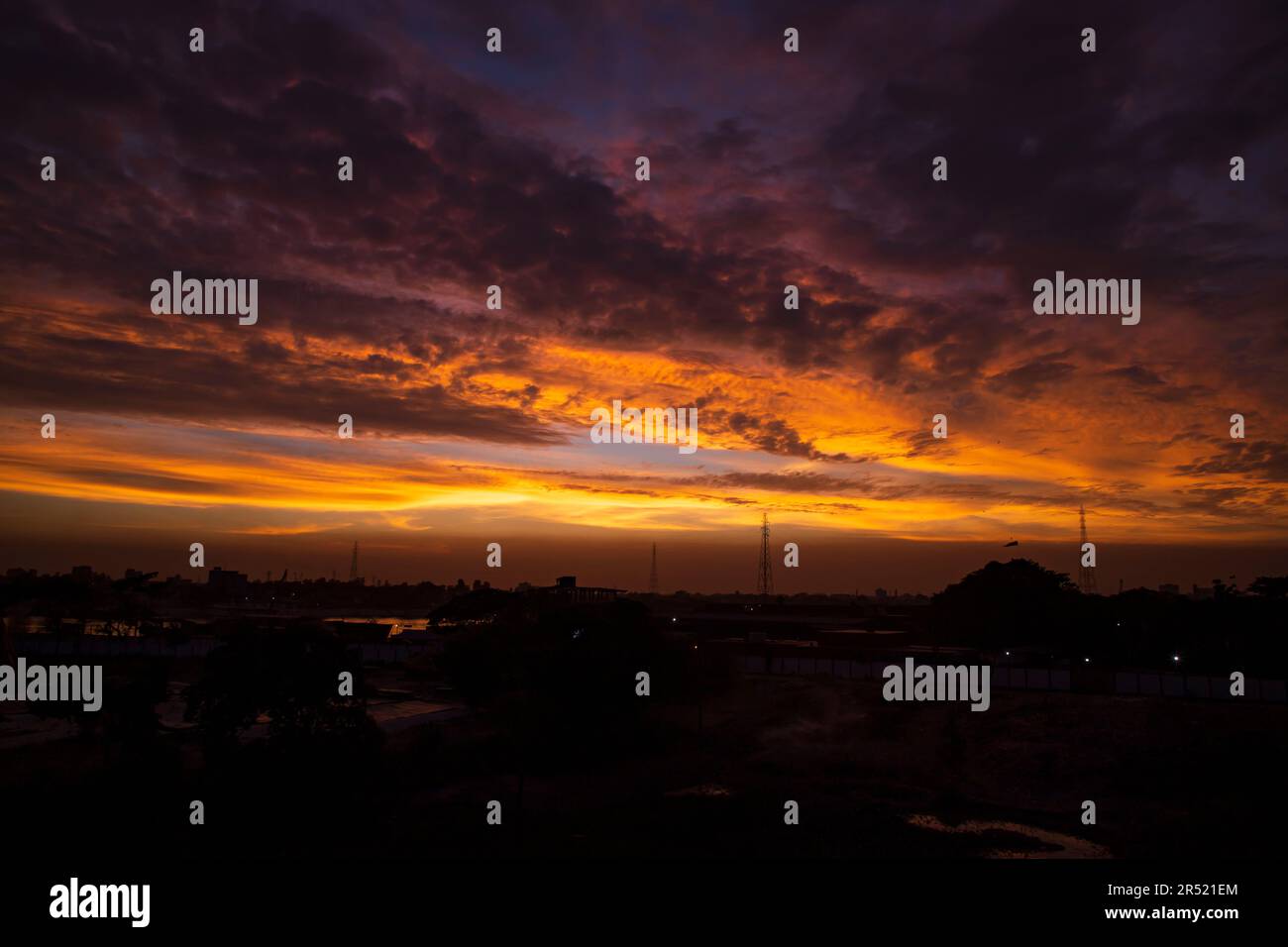 Sunset over the city, silhouette of a high voltage transmission tower ...