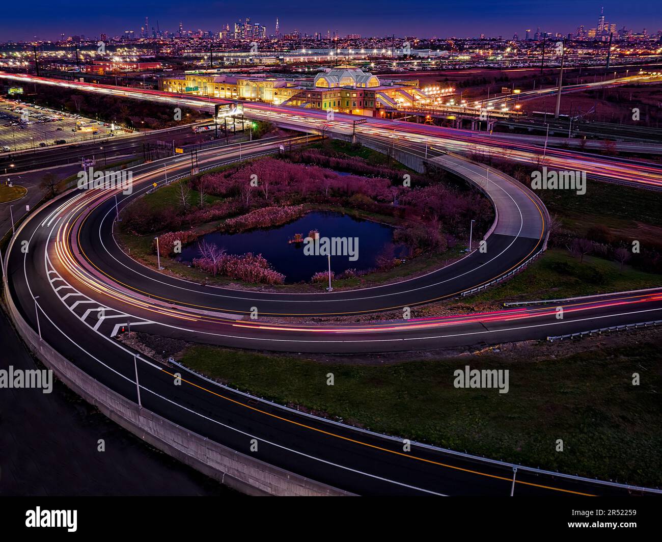 Secaucus Junction Station And NYC - Aerial long exposure view to the New Jersey Turnpike very long ramp, the illuminated train station along  with a v Stock Photo
